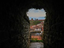 A view of a river and houses through a stone archway at Hazel Lodge in Whitby