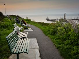 A pathway with benches and a pier at Hazel Lodge in Whitby