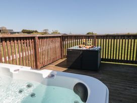 An outdoor area with a hot tub and a table set with food and drinks at Hazel Lodge in Whitby