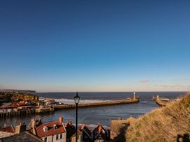 A view of a seaside with piers and houses at Willow Lodge in Whitby