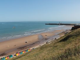 A beach with colorful huts and a pier at Willow Lodge in Whitby
