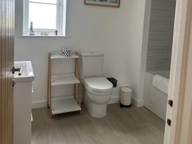 A bathroom with a toilet, shelf, and bathtub at 9 Coastguard Cottages in Woolacombe
