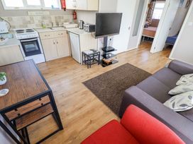 A kitchen and living area with a stove fridge sofa and television at 68 Cherry Park in Chapel St Leonards