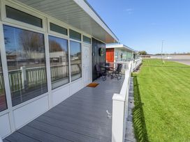 A porch with a table and chairs outside units with large windows at 68 Cherry Park in Chapel St Leonards