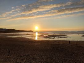 A beach at sunset with people walking and reflecting water at 33 Tre Lowen in Newquay