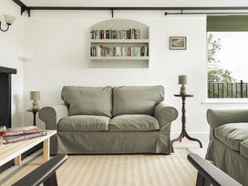 A living room with a sofa, lamp, and bookshelf at Tethers End in Lindeth near Bowness-On-Windermere