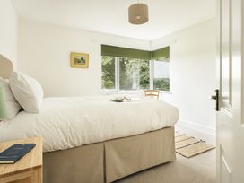 A bedroom with a bed, chair, and window at Tethers End in Lindeth near Bowness-On-Windermere