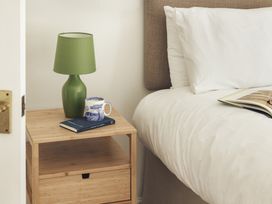 A bedroom with a lamp and a book on a nightstand at Tethers End in Lindeth near Bowness-On-Windermere