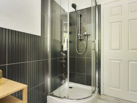 A bathroom with a shower enclosure and wooden shelf at Tethers End in Lindeth near Bowness-On-Windermere