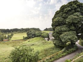 A view of a field with a tree and stone building at Tethers End in Lindeth near Bowness-On-Windermere