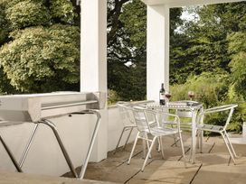 An outdoor seating area with a grill, table, and chairs at Tethers End in Lindeth near Bowness-On-Windermere