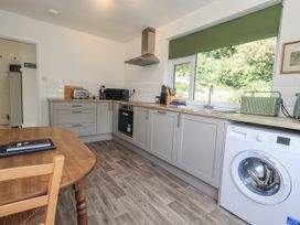 A kitchen with wooden table and washing machine at Tethers End Lindeth near Bowness-On-Windermere