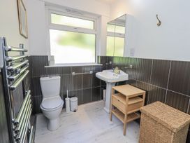 A bathroom with a toilet, sink, and storage furniture at Tethers End in Lindeth near Bowness-On-Windermere