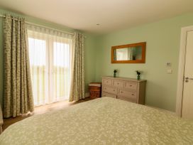 A bedroom with a window, dresser and mirror at Carrowmore North, Doonbeg, County Clare