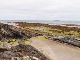A rocky shoreline with seaweed and a concrete path at Carrowmore North in Doonbeg, County Clare