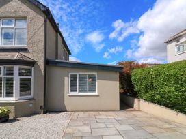 The side of a house with a paved patio area and gravel next to a hedge and shrubs at 3 Palms in Preston Sands