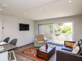 A living room with a leather sofa armchair coffee table and TV with vertical blinds at 3 Palms in Preston Sands