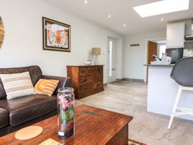 A living room with a brown leather sofa pillows a wooden coffee table with a glass jar and a chest of drawers with a lamp and wall art at 3 Palms in Preston Sands