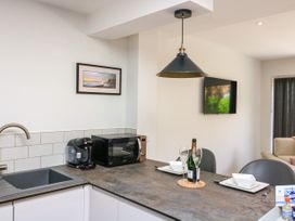 A kitchen area with a sink coffee machine microwave and a dining counter set with plates glasses and a bottle at 3 Palms in Preston Sands