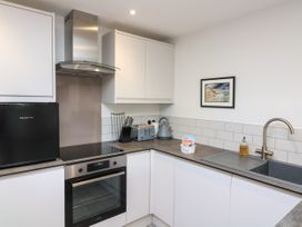 A kitchen with white cabinets a black mini fridge an oven stove a toaster a kettle a knife block a sink and a framed picture on the wall at 3 Palms in Preston Sands