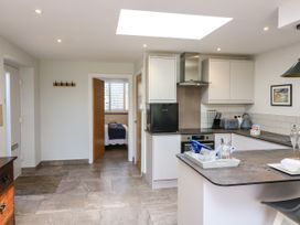A kitchen with white cabinets a small black fridge and an open door showing a bedroom at 3 Palms in Preston Sands