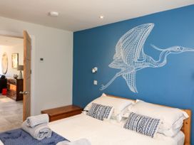 A bedroom with a bed with white bedding and blue patterned pillows under a blue wall with a bird drawing at 3 Palms in Preston Sands