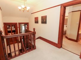 A hallway with a staircase and chandelier at Bracken Howe in Ambleside