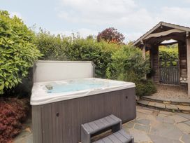 A hot tub with a wooden gazebo and plants at Bracken Howe in Ambleside