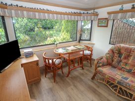 A sitting area with a table, two chairs, a patterned sofa, and a television at Lazy Trout Caravan Ludchurch near Narberth