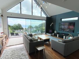 A living room with a sofa, coffee table, and television at Woodcroft in Pwllheli