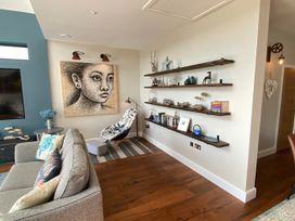A living room with a sofa and shelves at Woodcroft in Pwllheli