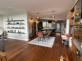 A living room with a dining table and shelves at Woodcroft in Pwllheli