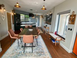 A dining room with a wooden table and chairs at Woodcroft Pwllheli