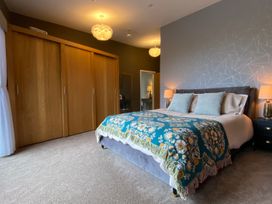 A bedroom with a bed, wardrobe, and lamps at Woodcroft in Pwllheli