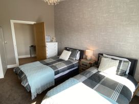 A bedroom with two beds and a bedside lamp at Woodcroft in Pwllheli