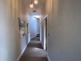 A hallway with stairs and paintings at Woodcroft in Pwllheli