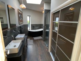 A bathroom with a bathtub and two sinks at Woodcroft in Pwllheli