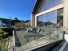 A deck with chairs and table at Woodcroft in Pwllheli