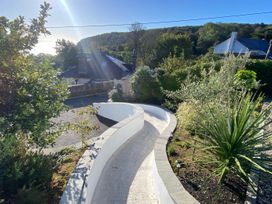 A pathway surrounded by plants and trees at Woodcroft in Pwllheli