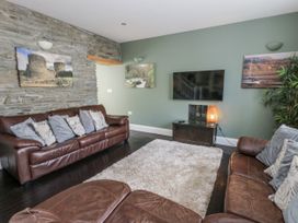 A living room with a sofa and a television at Station Hall in Cilgerran