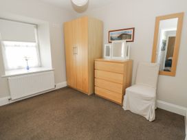 A bedroom with a wardrobe, chest of drawers, chair, and mirror at Station Hall in Cilgerran