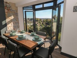 A dining room with a wooden table and green tableware at 9 Brython Place Tenby