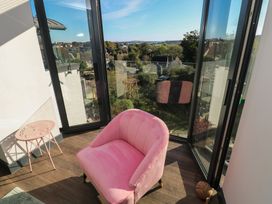 A sitting room with a pink chair and a table at 9 Brython Place in Tenby