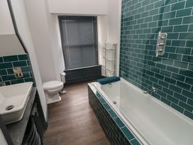 A bathroom with a bathtub, sink, toilet and radiator at 9 Brython Place Tenby