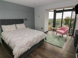 A bedroom with a bed and pink chair at 9 Brython Place in Tenby