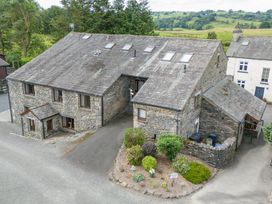 An exterior view of a stone building with trees and a garden at Hayloft at Pound Farm Crook near Kendal