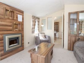 A living room with a fireplace armchair coffee table and glass cabinet at 31 Forest Views in Moota near Aspatria