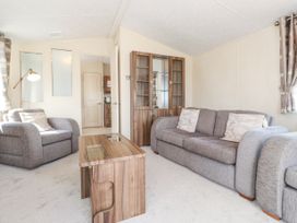 A living room with a sofa armchair coffee table and a cabinet at 31 Forest Views in Moota near Aspatria