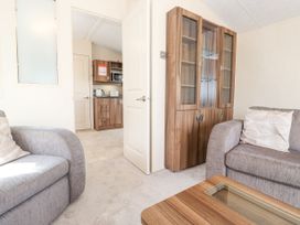 A living room with two gray sofas a wooden cabinet and a wooden coffee table with glass panel at 31 Forest Views in Moota near Aspatria