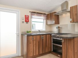 A kitchen with wooden cabinets a stainless steel stove sink and a door at 31 Forest Views in Moota near Aspatria